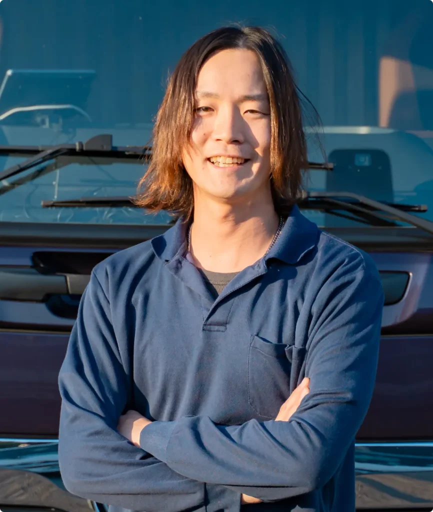 トラック前で腕を組み笑顔を向ける作業者