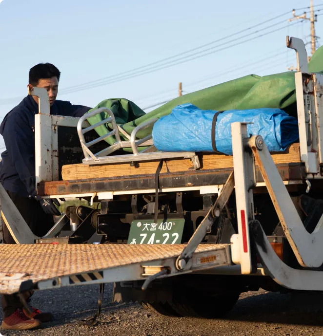 トラック荷台で荷物を固定する作業中の男性