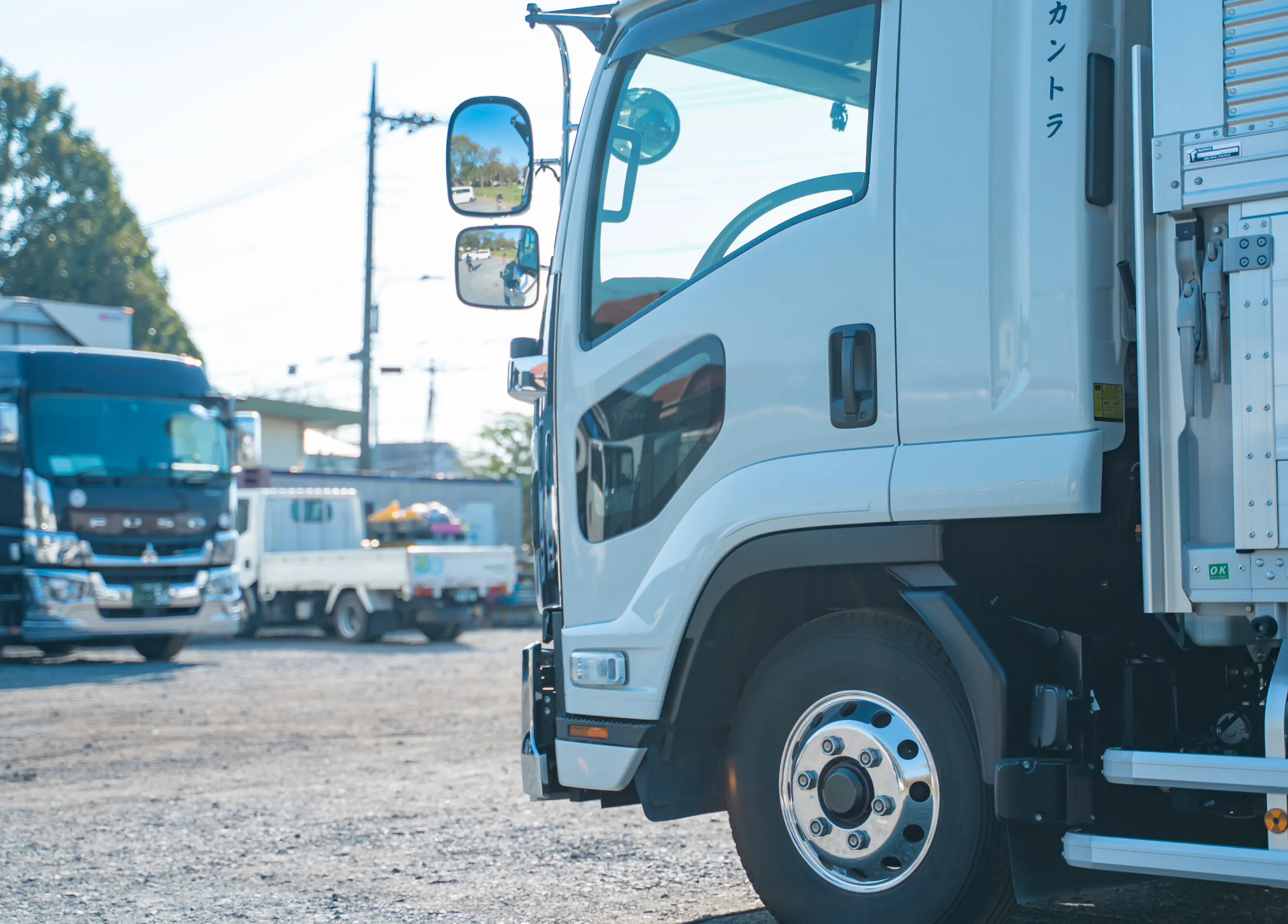 駐車場に並ぶ白い大型トラックの側面