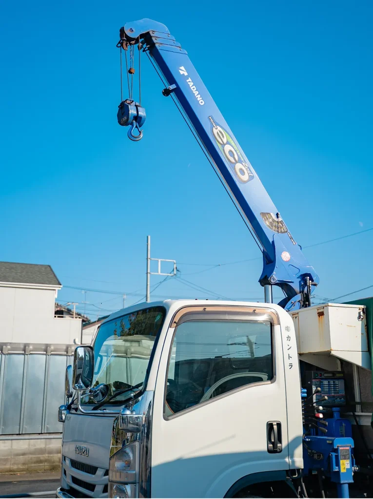 青空の下で伸びる青いトラッククレーンアーム