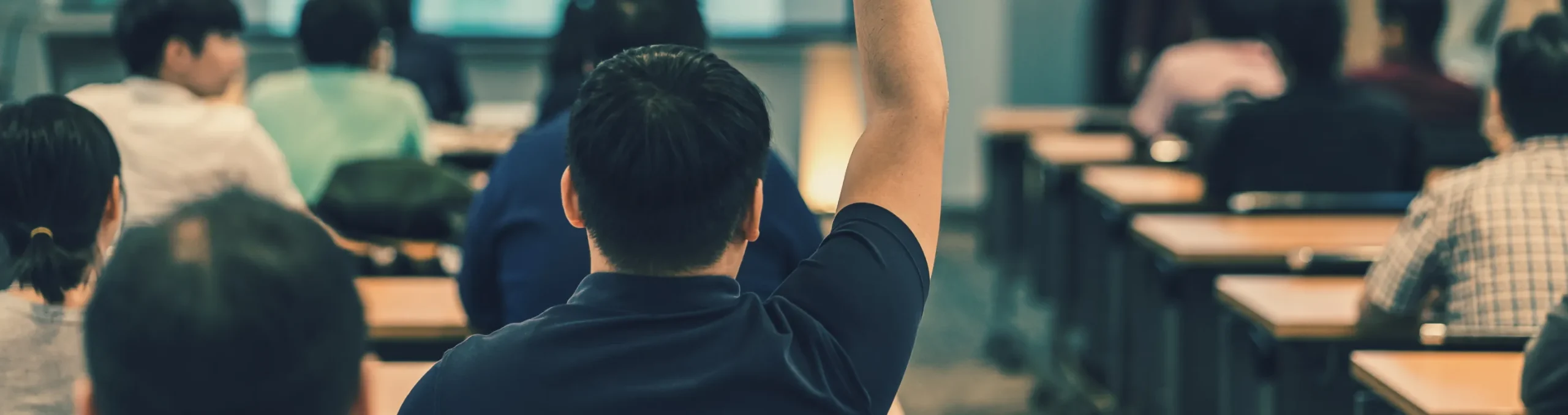 教室で手を挙げる人物を背後から見た光景