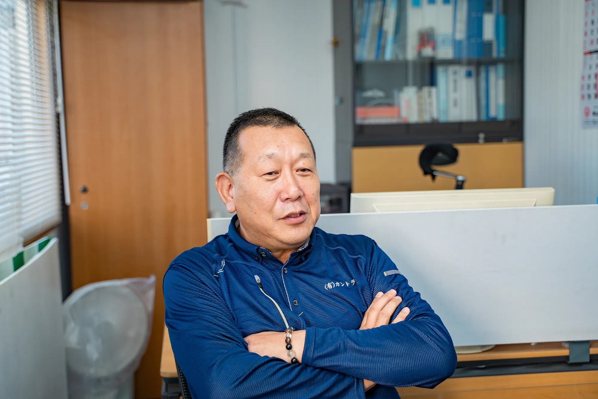 事務所で腕を組み談笑する作業服の男性