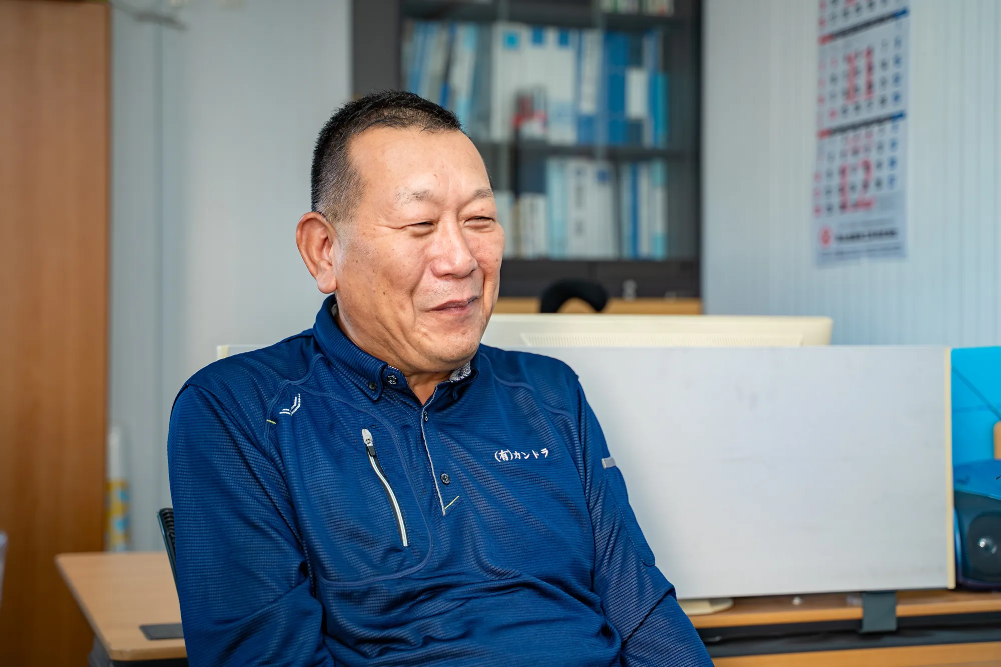 事務所で笑顔を見せる作業服の男性