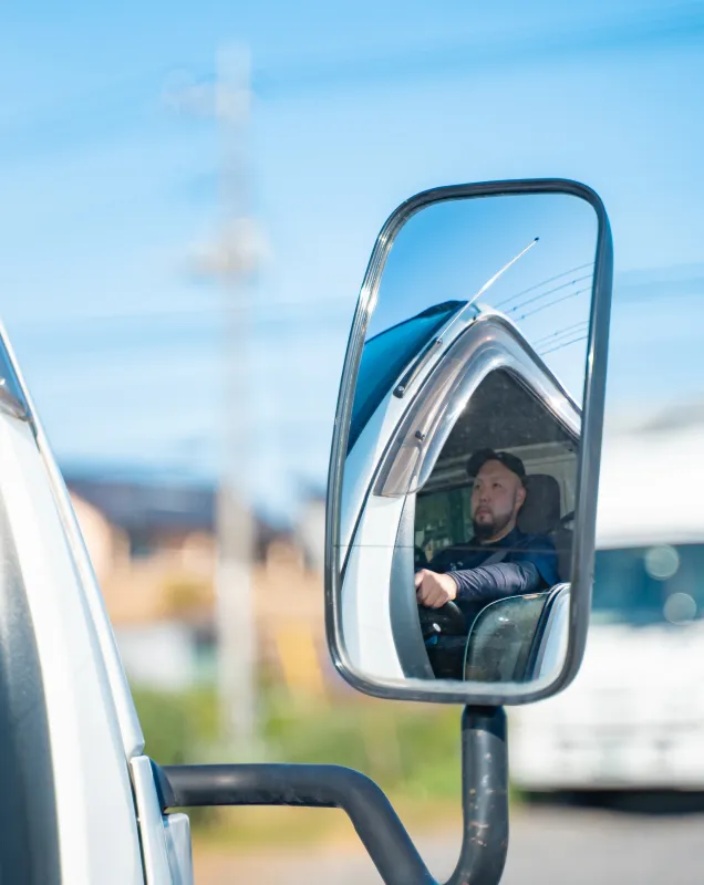 サイドミラーに映る運転中の作業者の姿