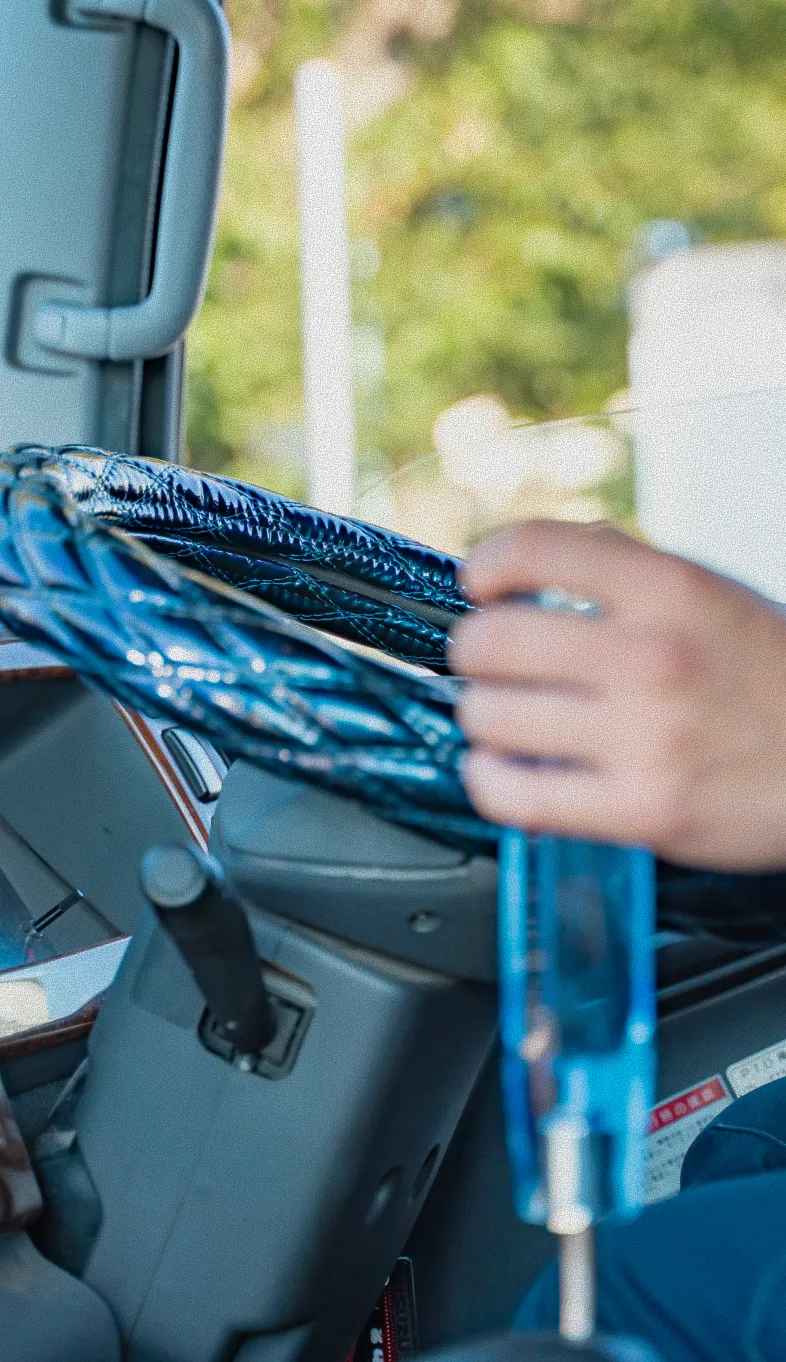 青いハンドルカバーのトラックを運転する人の手元