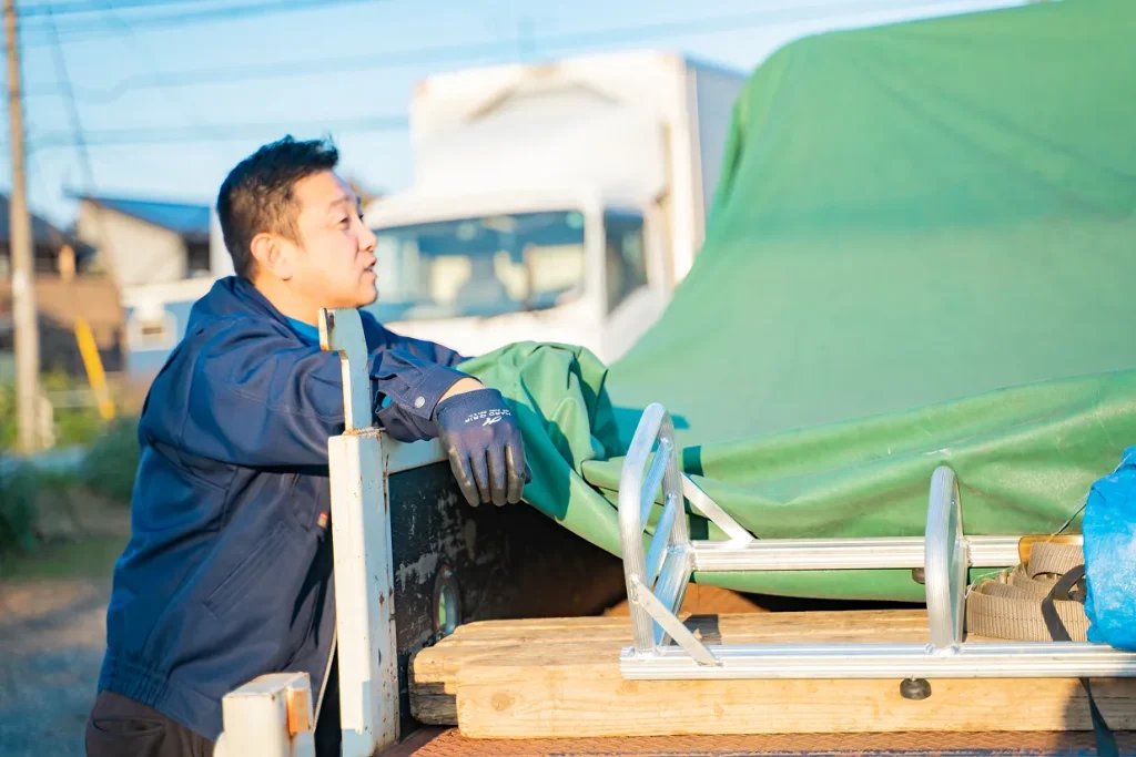 荷台に手をかける作業服姿の男性