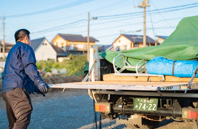 荷台後部で積載物を整える作業員の後ろ姿