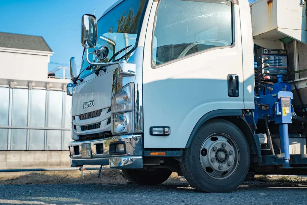 駐車場に停められた白い中型トラックの前方部分
